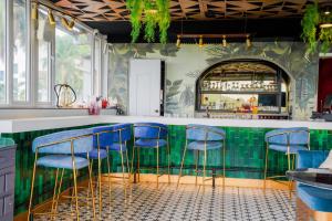 a bar with blue stools in a room with green tiles at SOLARAA iNN in Anjuna