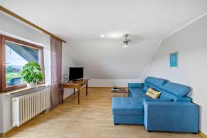 a living room with a blue couch and a desk at Ferienwohnung Panorama in Freiamt