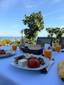 a table with plates of food on a table with the ocean at Perseku GuestHouse in Shirokë