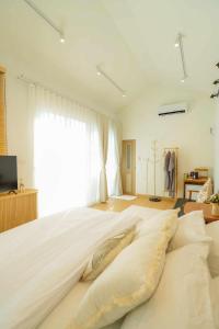 a bedroom with a large white bed with pillows at After Beach House Phla Resort in U-Tapao