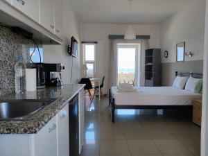 a room with a bed and a kitchen with a sink at Seaview Studio in Gázion