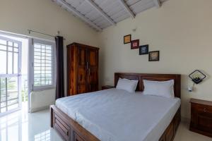 a bedroom with a large bed and a large window at Vrishti Homestay in Bhīm Tāl