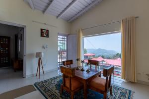 a dining room with a table and a large window at Vrishti Homestay in Bhīm Tāl