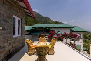 a patio with wicker chairs and a table on a balcony at Vrishti Homestay in Bhīm Tāl