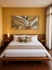 a bedroom with a large bed with a painting on the wall at Chalé da Árvore - Refúgio das Videiras in Moeda