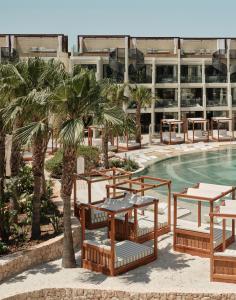 a resort with a pool and tables and palm trees at BLESS Ibiza The Site - New Opening 2026 in Playa d'en Bossa