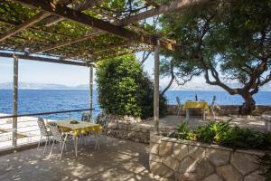 een patio met een tafel en stoelen en de oceaan bij Guest House Hazdovac in Kozarica