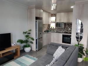 a living room with a couch and a kitchen at The Room Above in Brackenfell