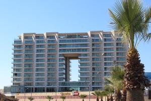 a tall building with a palm tree in front of it at First Class Marina Herzlia in Herzelia 