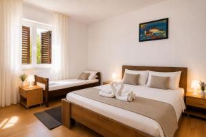 a bedroom with two beds and two windows at Apartmani Bonaca in Pakoštane
