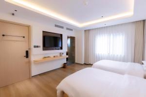 a hotel room with two beds and a flat screen tv at Hera Hotel in Hanoi
