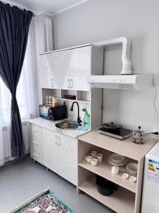 a small kitchen with white cabinets and a sink at Gatto in Bishkek