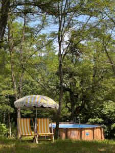 two chairs under an umbrella next to a house at Jvarisa Glamping in Ambrolauri