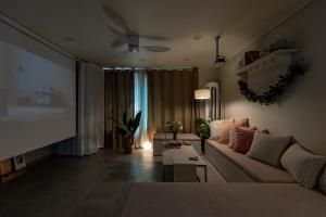 a living room with a couch and a projection screen at 김포공항ㆍ까치산역ㆍ최대11명ㆍ3룸화2ㆍ각방에어컨ㆍ2층독채 in Seoul