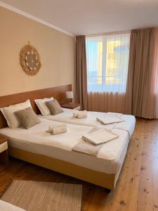 a bedroom with two beds and a large window at Къща за гости Смокиня in Obzor