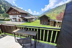a balcony with a wooden table and a house at Studio at the foot of the ice rink in Le Grand-Bornand +1 photo