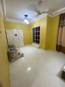 an empty room with yellow walls and white tile floors at شقة عوقد in Okkad