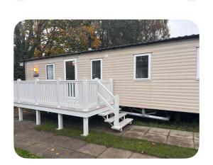 a mobile home with a white railing and a porch at Explorer45 in Lytchett Minster