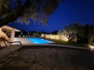 a swimming pool at night with chairs around it at Olive Treasure Villa with Private Pool in Kolymbia