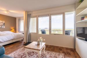 a bedroom with a bed and a tv and windows at Appartementencomplex Juliana 108 in De Koog