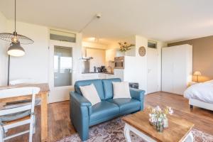 a living room with a blue couch and a bed at Appartementencomplex Juliana 108 in De Koog