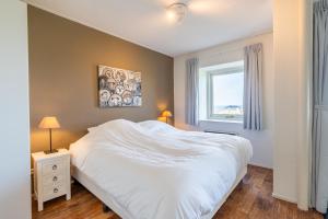 a bedroom with a white bed and a window at Appartementencomplex Juliana 108 in De Koog