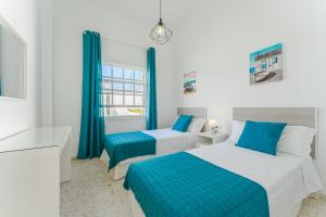a bedroom with two beds and blue curtains at BUNGALOW ATALAYA in Abades