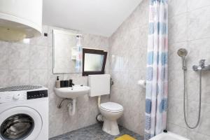 a bathroom with a toilet and a sink and a washing machine at Apartmani Bonaca in Pakoštane +28 photos