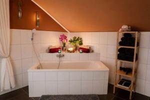 a white tub in a bathroom with a shelf at Ferienwohnung Blumäcker Oberbayern in Oberhausen