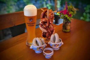a wooden table with a glass of beer and pretzels and a pretzel at Ferienwohnung Blumäcker Oberbayern in Oberhausen