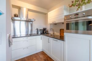 a kitchen with white cabinets and stainless steel appliances at Appartementencomplex Juliana 108 in De Koog +5 photos