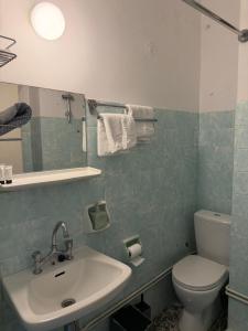a bathroom with a sink and a toilet and a mirror at Puente Rooms in Methana