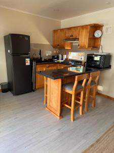 a kitchen with a black refrigerator and wooden cabinets at Cabañas Puchuman Lican Ray in Licán Ray