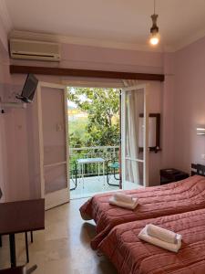 a bedroom with two beds and a sliding glass door at Puente Rooms in Methana