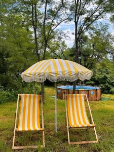 two chairs sitting under an umbrella in the grass at Jvarisa Glamping in Ambrolauri