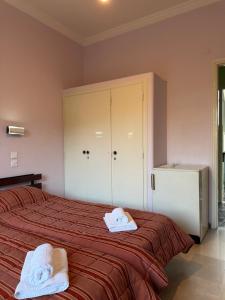 a bedroom with a bed with two towels on it at Puente Rooms in Methana +12 photos