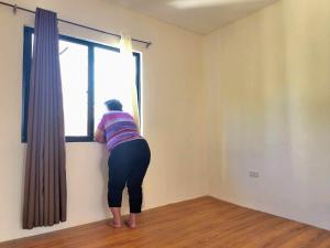 a woman is looking out of a window at Sta Cruz Laguna Transient House in Santa Cruz
