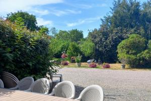 a row of white chairs sitting in a garden at la ferme des tertres in La Chapelle-près-Sées