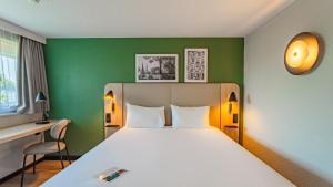 a bedroom with a bed and a green wall at Campanile NATURE - Biarritz in Biarritz