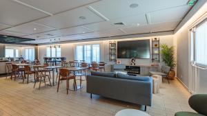 a restaurant with tables and chairs and a flat screen tv at Campanile NATURE - Biarritz in Biarritz
