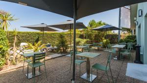 a group of tables and chairs with umbrellas at Campanile NATURE - Biarritz in Biarritz