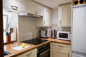 a kitchen with white cabinets and a white microwave at NEW Stylish Cosy Dog Friendly Cottage Parking Central in Oundle
