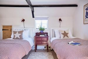 a bedroom with two beds and a nightstand between them at NEW Stylish Cosy Dog Friendly Cottage Parking Central in Oundle