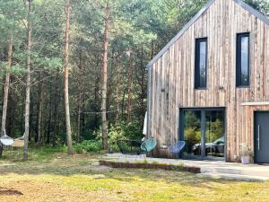 a wooden house in the woods with two chairs at Forest Cabin Modern Barn and Private Woods in Jamielnik
