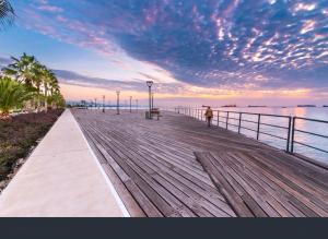 a person walking on a wooden boardwalk near the water at Niko's Modern Family Home near the Beach in Limassol