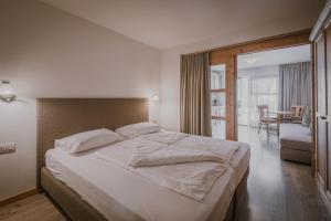 a bedroom with a large white bed and a dining room at Appartement & Hotel Innerhofer in Gais