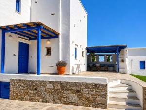 a white house with blue doors and a stone wall at villa kite paros in Pounda +7 photos