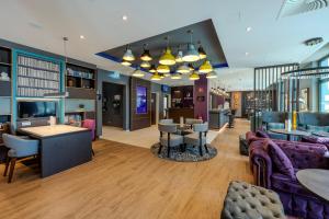 a living room with a couch and tables and chairs at Premier Inn Bremerhaven in Bremerhaven
