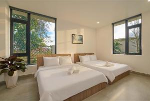 two beds in a room with two windows at Duck House in Da Thien