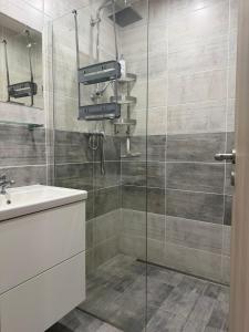 a bathroom with a glass shower with a sink at Apartman VIKY in Bartovice